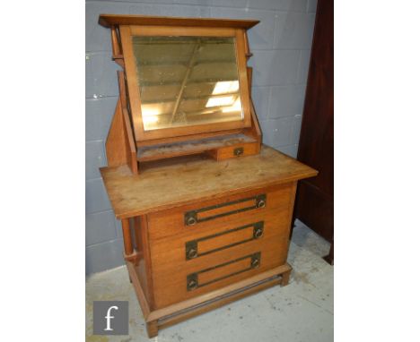 In the manner of Liberty and Co - An oak dressing chest, fitted with a swing mirror above three long drawers with copper stra