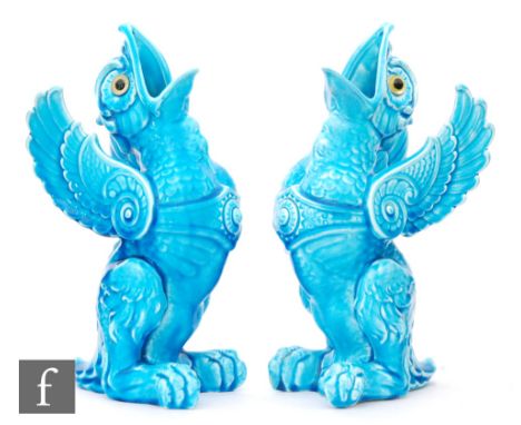 In the manner of Burmantofts - A pair of late 19th Century pottery vases in the form of griffins, relief moulded with mouths 