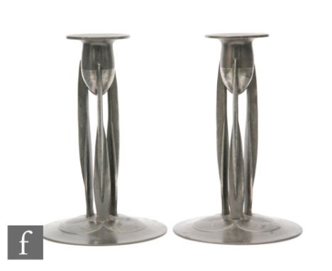 Archibald Knox for Tudric - A pair of model 0223 pewter candlesticks, each raised to three strut type supports over stylised 