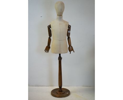 Child Shop Mannequin with articulated wooden arms, cloth body and raised on a turned wooden base, 144cms high 