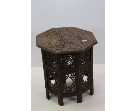 Indian hardwood Octagonal Table, heavily carved with flowers and foliage to top and raised a folding carved octagonal base, 5