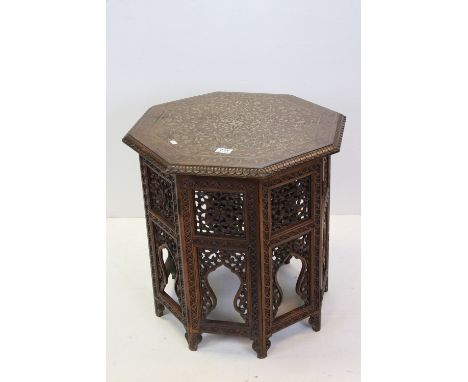 Indian Hardwood Octagonal Table , the top with foliate brass inlay, raised on a folding carved base, 56cms wide x 58cms high 