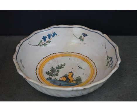 A vintage tin glaze bowl with central scene and floral surround. 