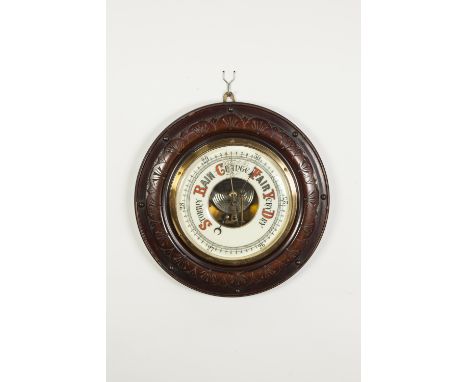 EARLY TWENTIETH CENTURY ANEROID BAROMETER in turned mahogany stained carved fruitwood surround, 13 1/3" (34.3cm) diameter 