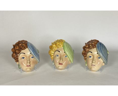 A group of three Beswick Art Deco pottery female face masks Two brunettes with blue berets and green earrings, the other a bl