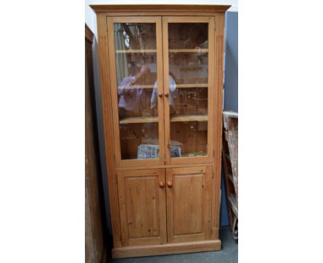 A pine glass fronted bookcase with three shelves, with a cupboard below with one shelf, 90x190cmH