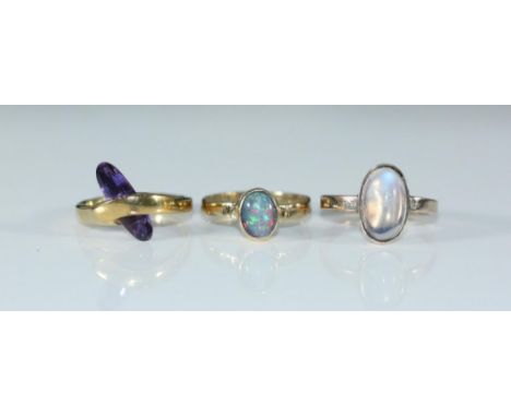 A 9ct gold ring set with an oval opal, size O/P, together with two various yellow metal rings set with purple and pale purple