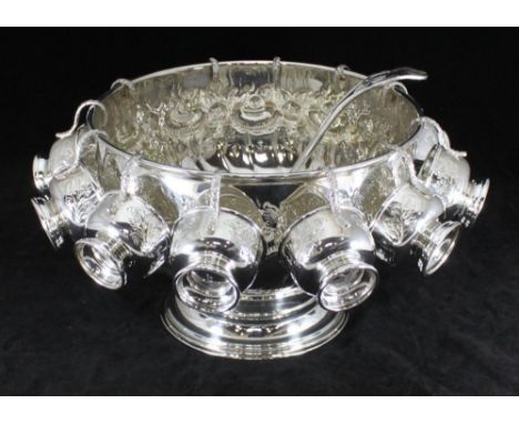 A silver-plated punch bowl of circular form raised on circular foot with rococo embossed decoration, together with twelve mat