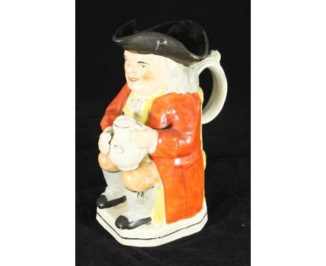 A 19th century Staffordshire pottery 'Squire' jug of typical form, seated wearing tricorn hat with ale jug and pipe, 25cm hig