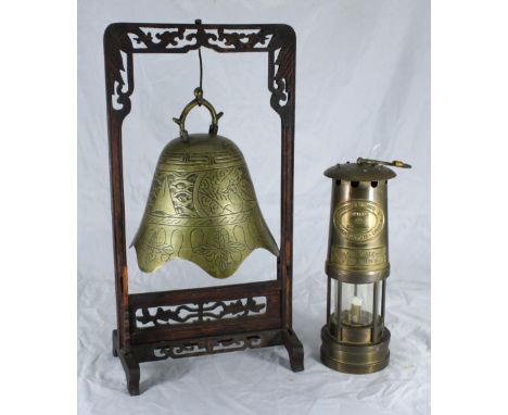 A Chinese brass table gong in the shape of a bell, engraved with mythical beasts and geometric designs suspended on carved wo