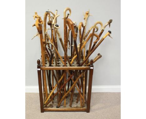 A good collection of 34 assorted carved walking sticks, variously mounted with antler-handles, some inset with coins and capp