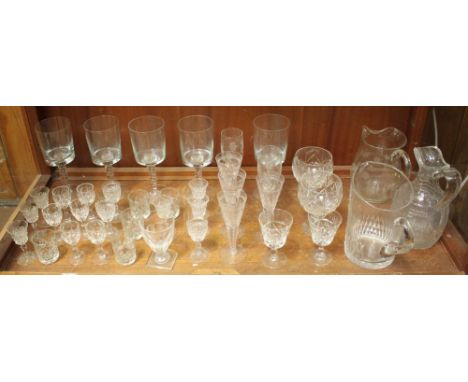 A shelf of assorted crystal glassware including five large twist-stemmed wine glasses, sherry glasses and small wine glasses 