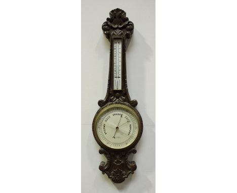 A late Victorian stained and carved oak aneroid wheel barometer and thermometer, by T.L. Ainsley of Cardiff, Barry and Newpor