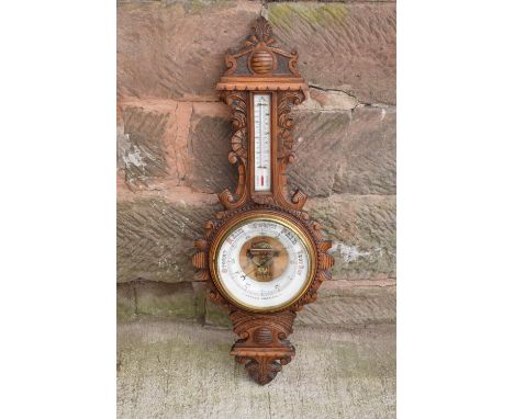 A late Victorian/ Edwardian arts and crafts style carved aneroid barometer. 109cm tall. There are some hairline cracks to the
