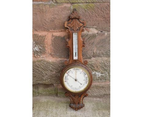 A late Victorian/ Edwardian arts and crafts style carved aneroid barometer. 105cm tall. There are some hairline cracks to the