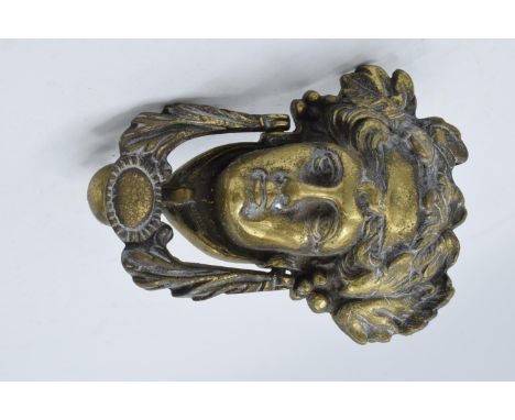 A cast brass door knocker in the form of a figural head. 17cm tall. 