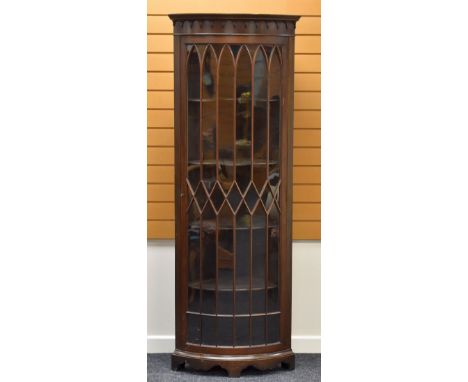 A BOW FRONTED STANDING CORNER CABINET having a single glazed door, geometrically divided and with classical detail to the cor