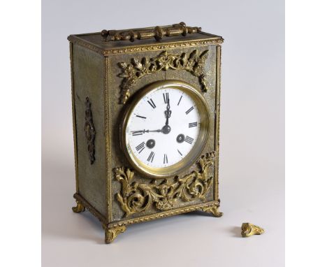 A BRASS ENCASED MANTEL CLOCK having a circular white dial bearing Roman numerals and handle to the top, raised on scroll feet