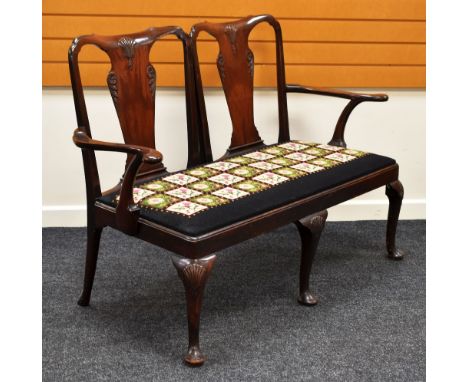 AN EDWARDIAN MAHOGANY ELBOW SOFA having carved and shaped backs and cabriole supports with floral tapestry seat