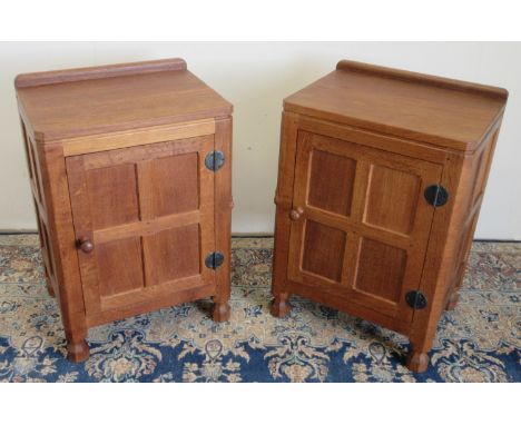 Robert Mouseman Thompson of Kilburn - a pair of adzed oak panelled bedside cupboards, with upstand, metal hinges and turned w