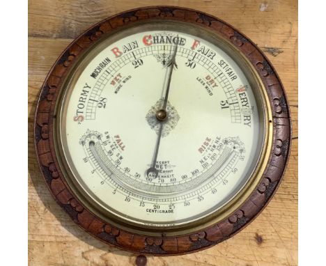 Edwardian Aneroid barometer, circular white dial with thermometer and brass bezel, in leaf carved oak frame, D34cmShipping £3
