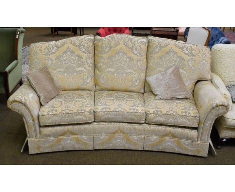 A three-seater sofa, modern, of curved form, upholstered in yellow and gold floral fabric, with six removable cushions, two s