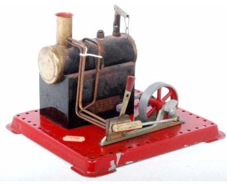 A small Mamod stationary steam engine with horizontal boiler driving a separate flywheel to power machinery, complete with sc