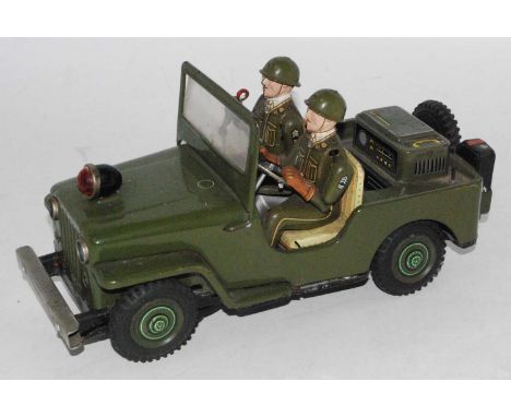 A TN Nomura tinplate and battery operated model of a military jeep with driver and attendant figure, finished in green with c