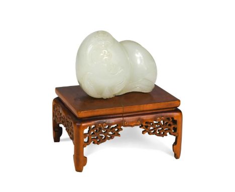 A Chinese jade carving of two peaches, Qing Dynasty, 18/19th century, with bats, one holding a coin, and foliage adorning the