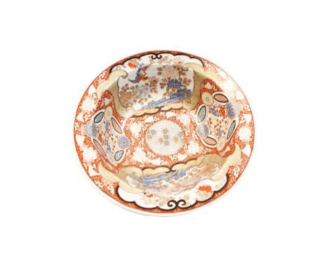 A Japanese porcelain water basin, circa 1900, circular with broad flange richly decorated with panels of birds among blue peo