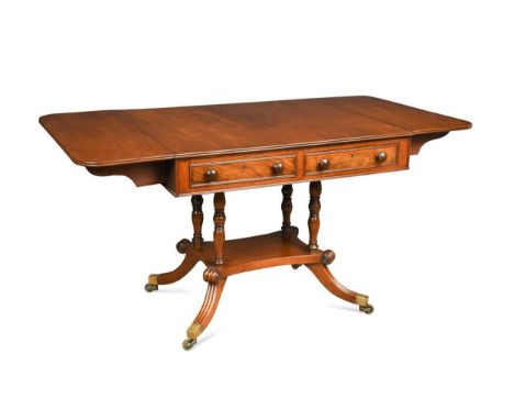 A Regency mahogany sofa table, the rounded rectangular drop flap top upon four turned column supports raised on four hipped s