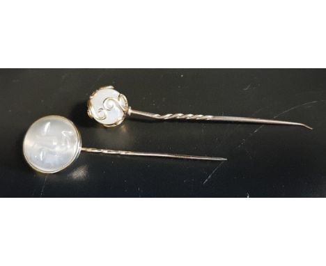 TWO MOONSTONE SET STICK PINSboth in unmarked gold, one with moonstone ball finial and overlaid gold scroll detail, the other 