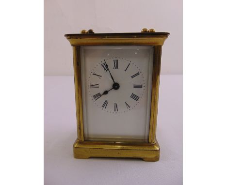 A brass carriage clock of customary form white enamel dial with Roman numerals