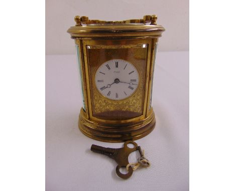 A Simmons shaped oval brass carriage clock with white dial and Roman numerals to include key