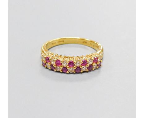 A modern 18ct gold, ruby and diamond set two row half hoop ring, size O, gross 5.3 grams.