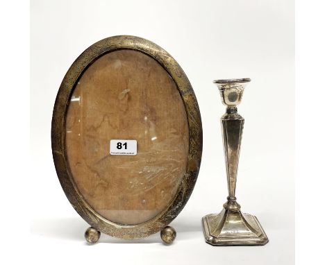A large silver photo frame, H. 29cm. (Stamped sterling) Together with a hallmarked silver candlestick.