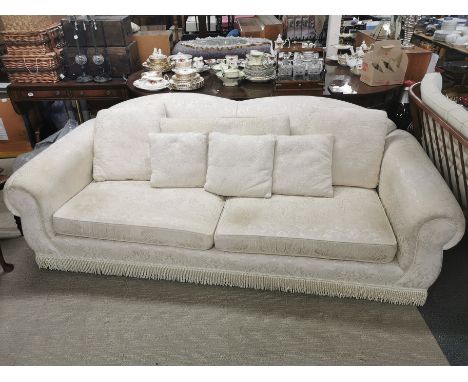 A large cream floral upholstered sofa/ settee with tassel borders, 220 x 100 x 80cm.