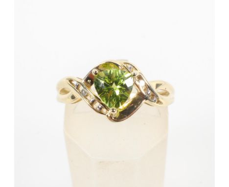 A yellow metal ring set with a heart cut peridot and finished with a single cut diamond to each shoulder. No hallmark - stamp