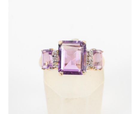 A yellow metal ring set with three graduated rectangular cut amethyst interspaced with a trio of single cut diamonds. Hallmar