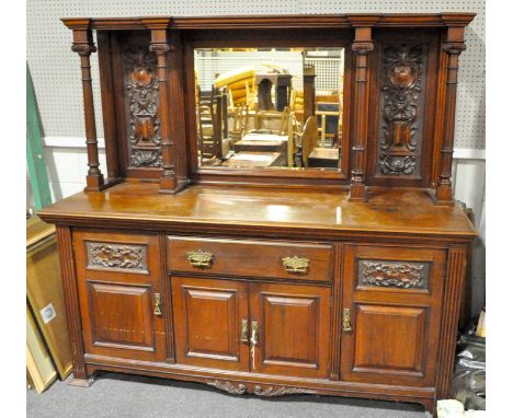 A large Victorian carved mahogany sideboard, late 19th century, with mirrored back flanked by reeded columns and carved folia