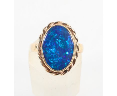 A yellow metal ring set with an oval cabochon cut synthetic black opal. Hallmarked 9ct gold, London. Size: K 3.1 grams