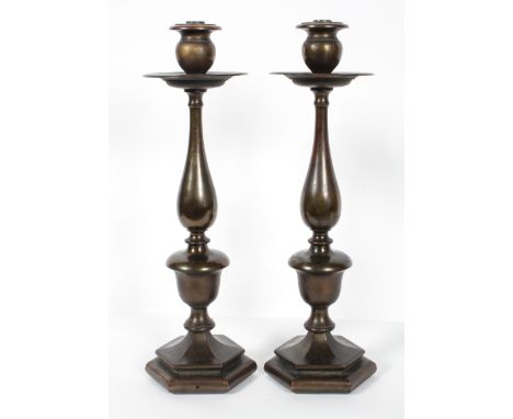 A pair of bronzed metal lamp bases, of 18th century form, with a broad drip tray above a baluster column and hexagonal foot, 