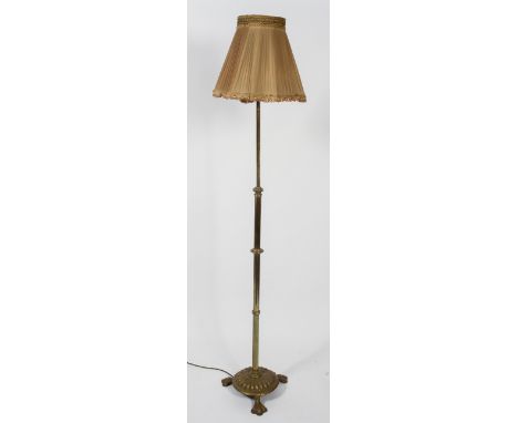 An Edwardian brass standard lamp, the adjustable stem with gadrooned ornament, on gadrooned domed base with three spreading f