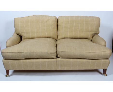 A Howard and Son style loose cushion three seater sofa with double hipped back and low arms to a deep seat base, raised on ma