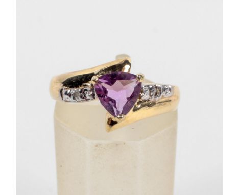 A yellow metal ring. Set with a trilliant cut amethyst and finished with illusion set diamond shoulders. Hallmarked 9ct gold,