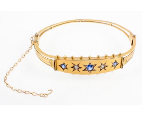 A 9ct yellow gold, 19th century hinged bangle, of openwork form, set a bead edged panel with three sapphires and two diamonds