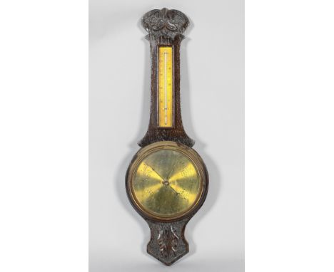 A late Victorian oak cased banjo wall barometer, with brass dials, the dark stained case carved with leaves and scrolls to th