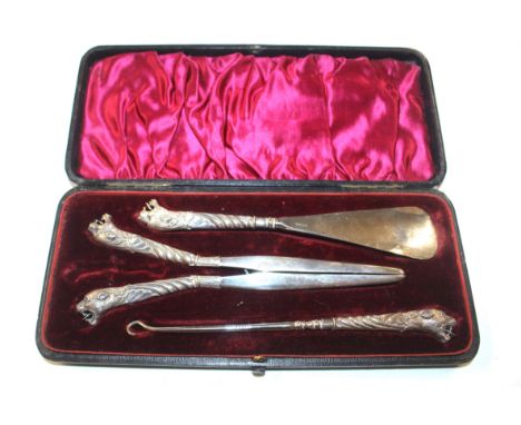 An Adie &amp; Lovekin, Birmingham cased silver beast head decorated shoe horn, glove stretcher, and button hook set