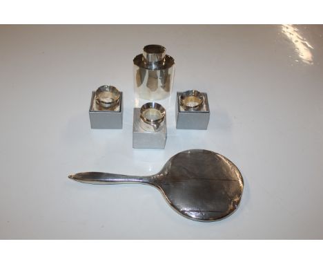A silver caddy, approx. 111gms; a silver backed hand mirror and three silver napkin rings 