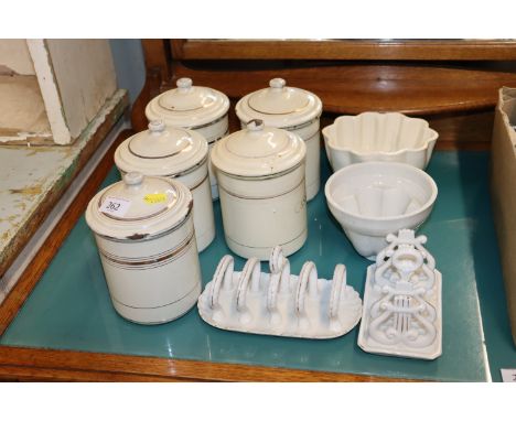 Two jelly moulds; two toast racks and five enamel storage jars 